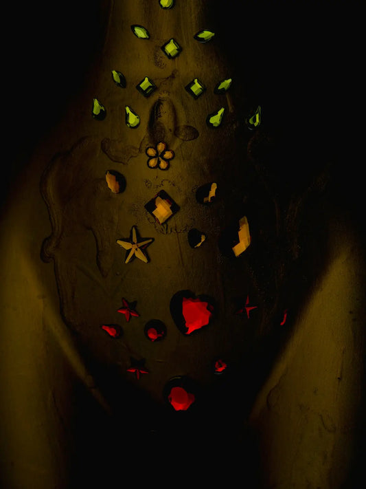 a person holding a lit up vase in the dark