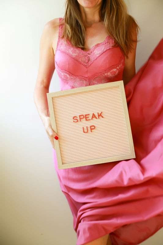 Woman holds sign that says speak up.