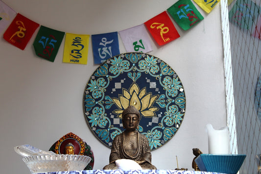 Buddha statue with prayer flags and lotus mandala.
