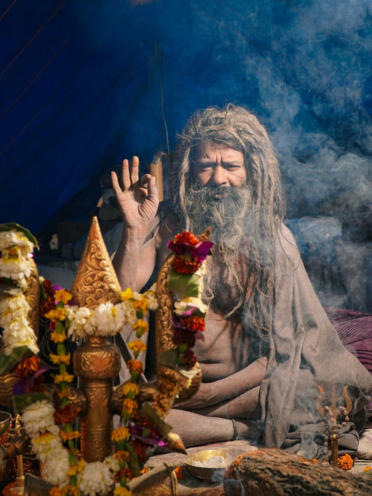 Man with long hair and beard, meditating with smoke.