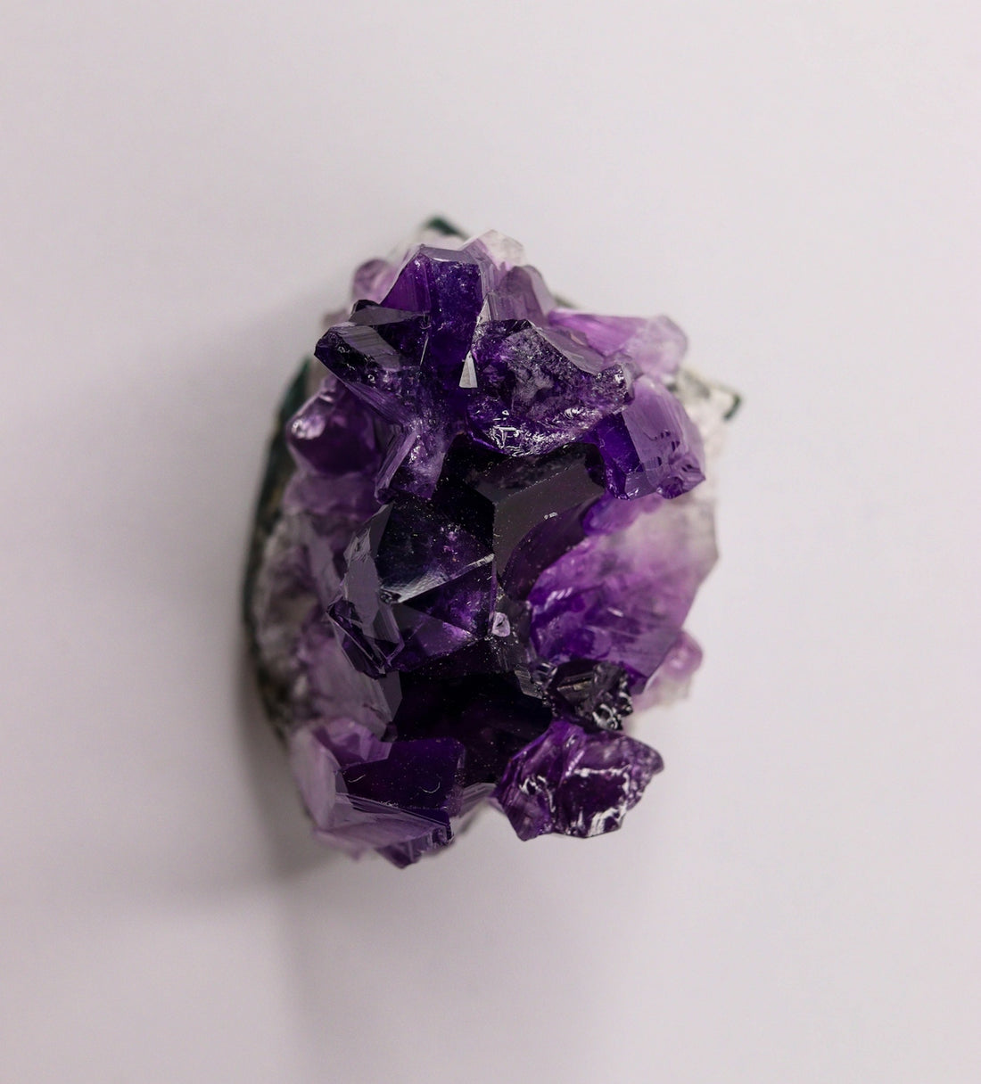 A vibrant purple amethyst crystal geode on a white background.