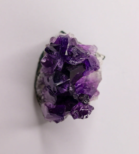 A vibrant purple amethyst crystal geode on a white background.