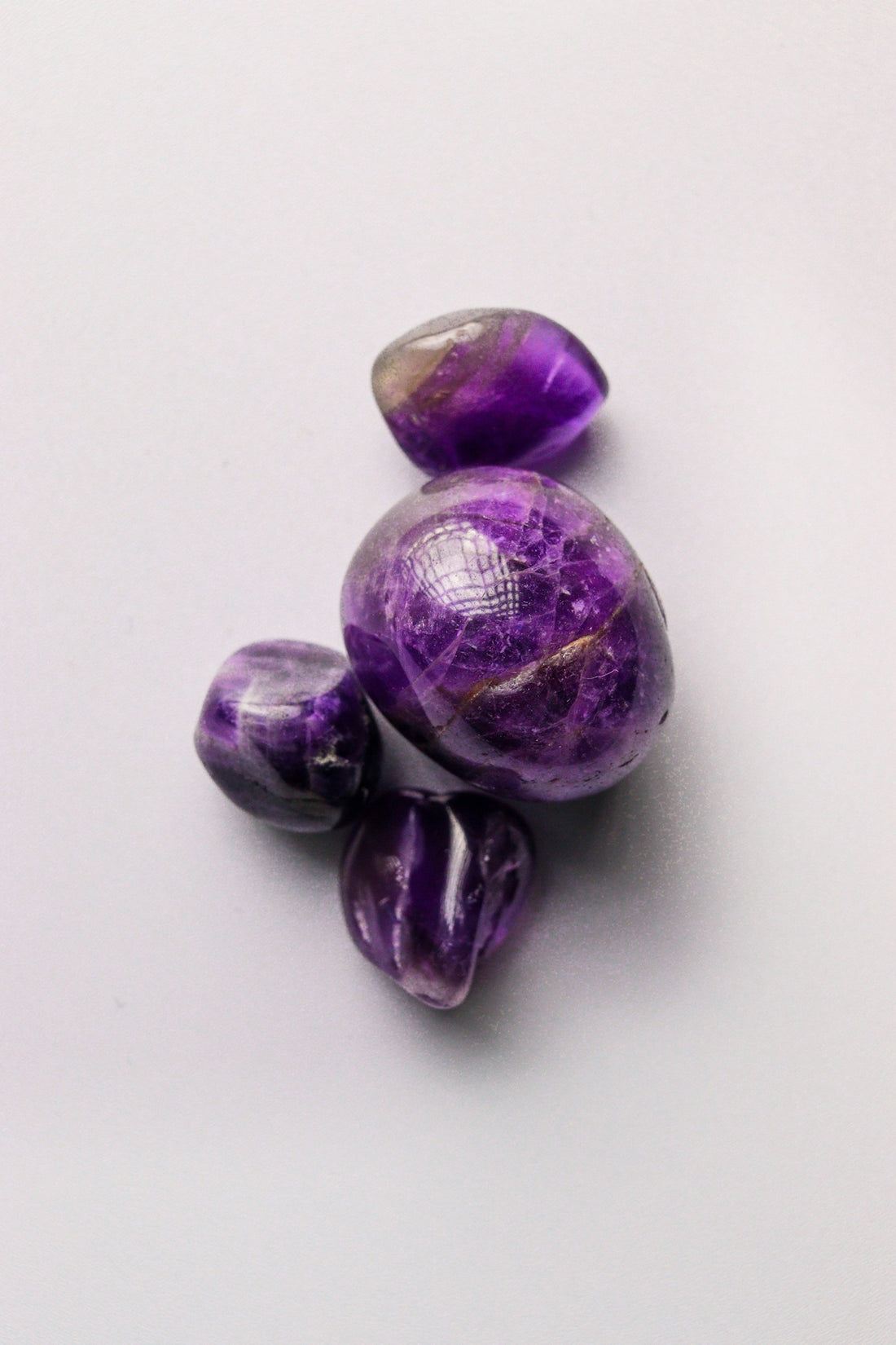 Several polished purple amethyst stones on a white background.