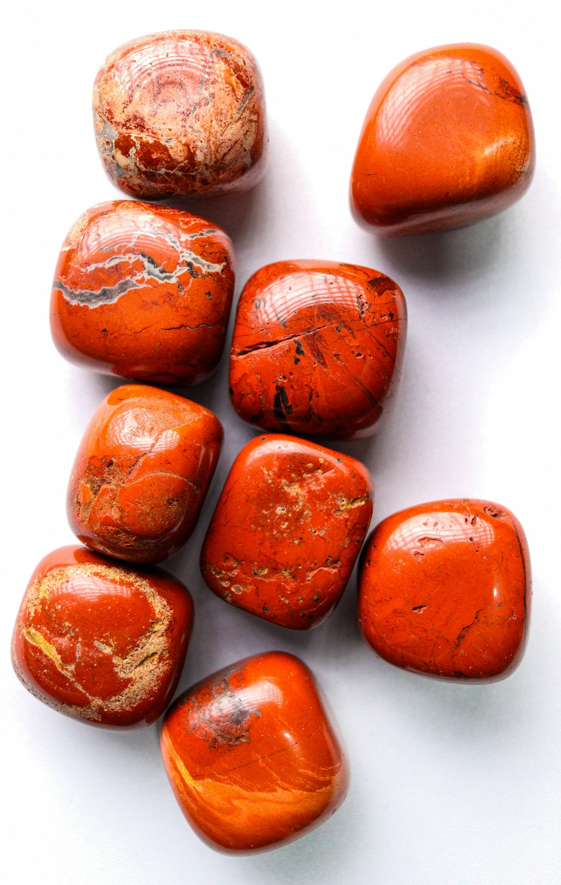 Collection of polished red jasper gemstones on white.