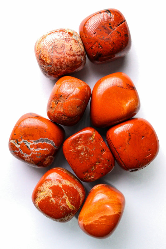 Several tumbled red jasper stones on a white background.
