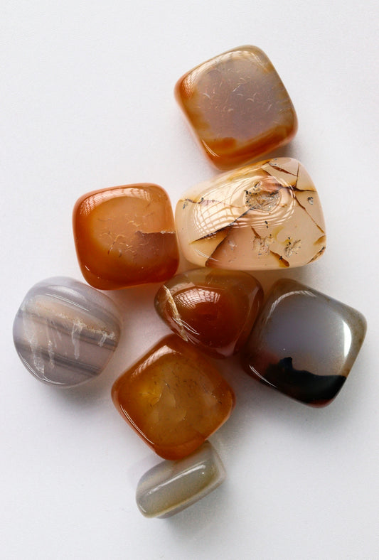 Polished agate and carnelian gemstones on a white surface.
