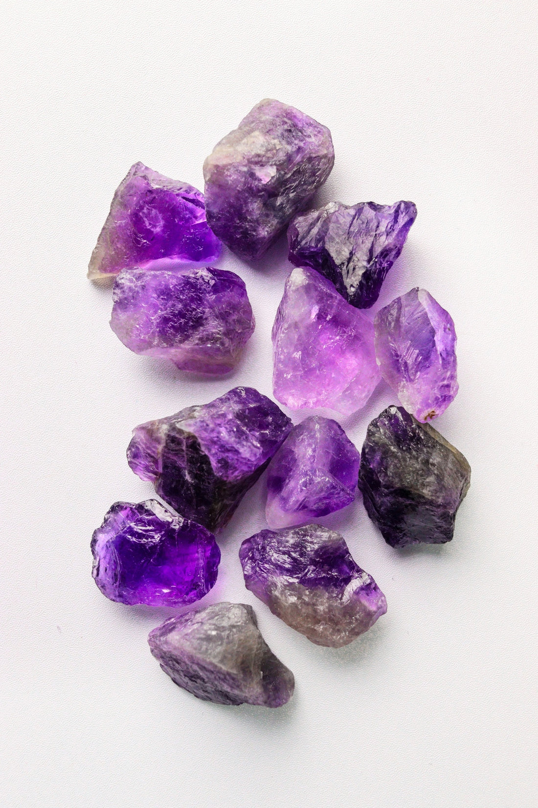 Raw purple amethyst crystals scattered on a white background.