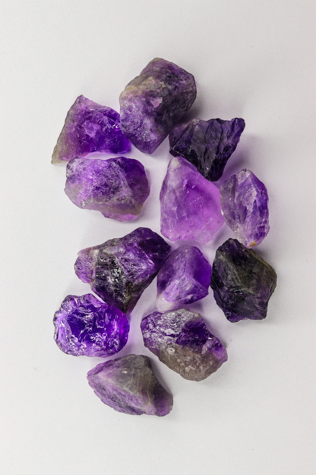 Raw amethyst crystals scattered on a white background.