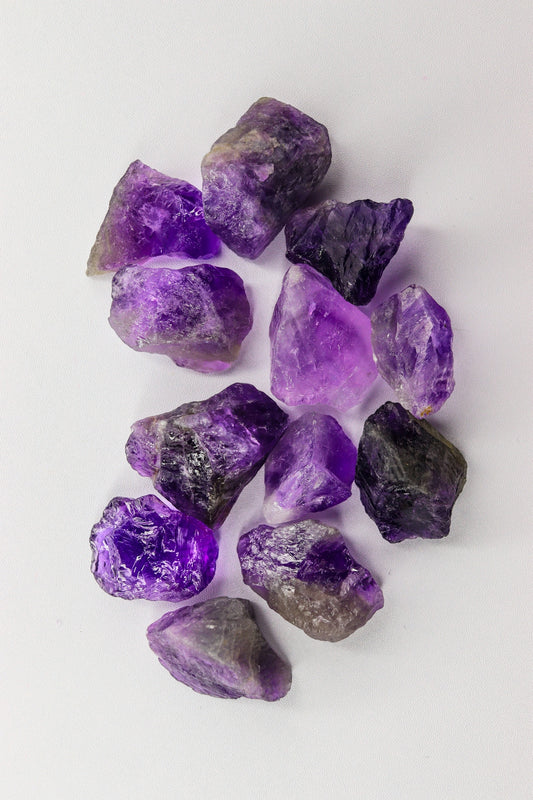 Raw amethyst crystals scattered on a white background.