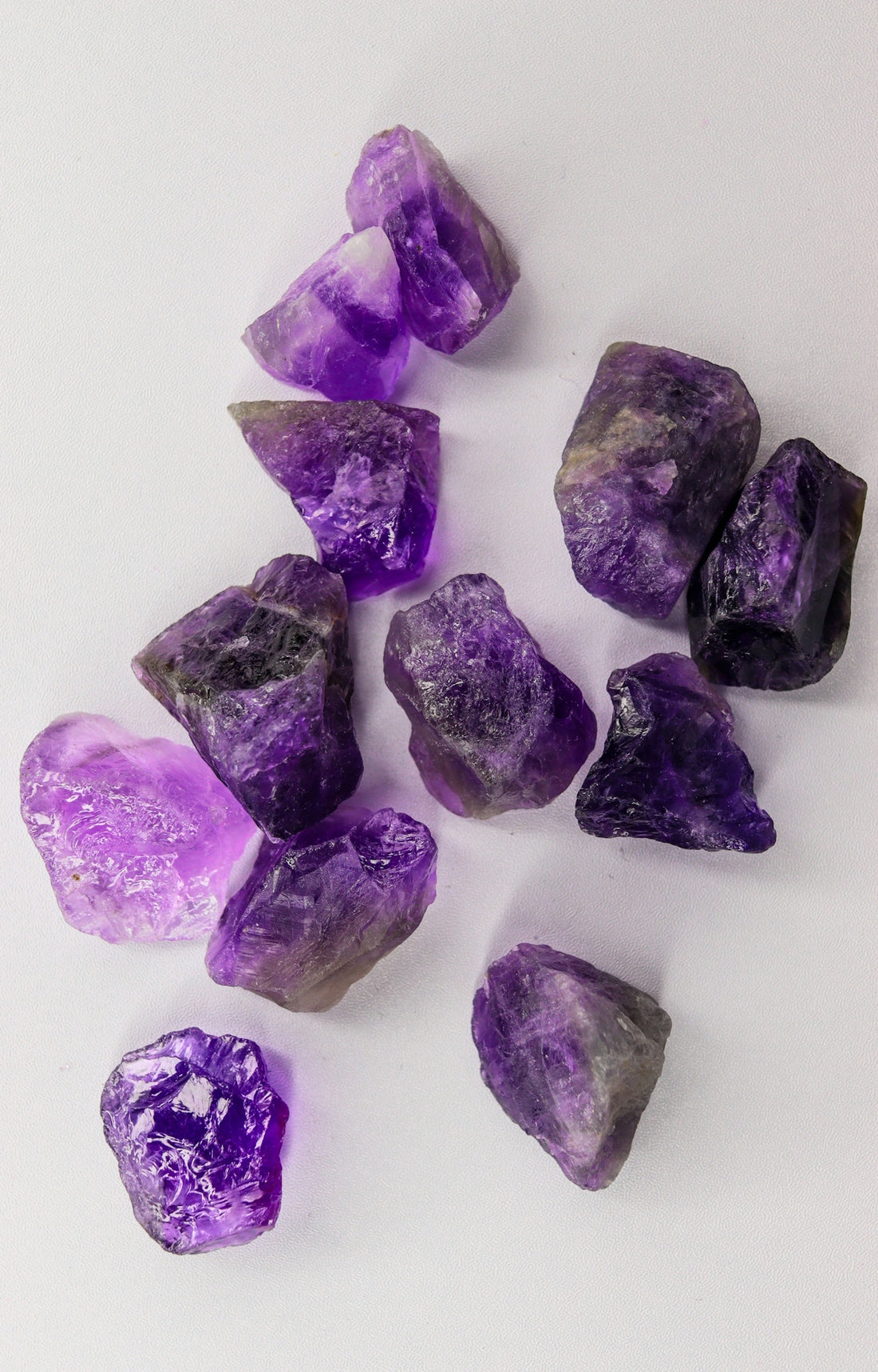 Raw amethyst crystals scattered on a white background.